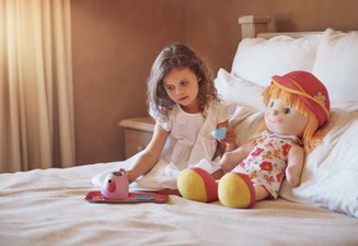 criança na cama ao lado de boneca de pano