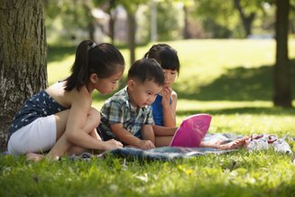 crianças na grama usando laptop infantil