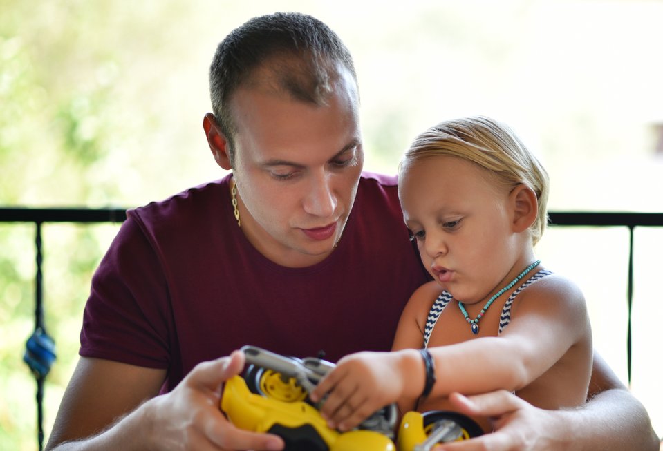 adulto e criança com uam mini moto nas mãos