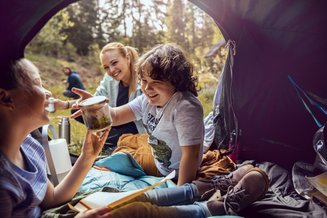 três pessoas em camping dentro de barraca