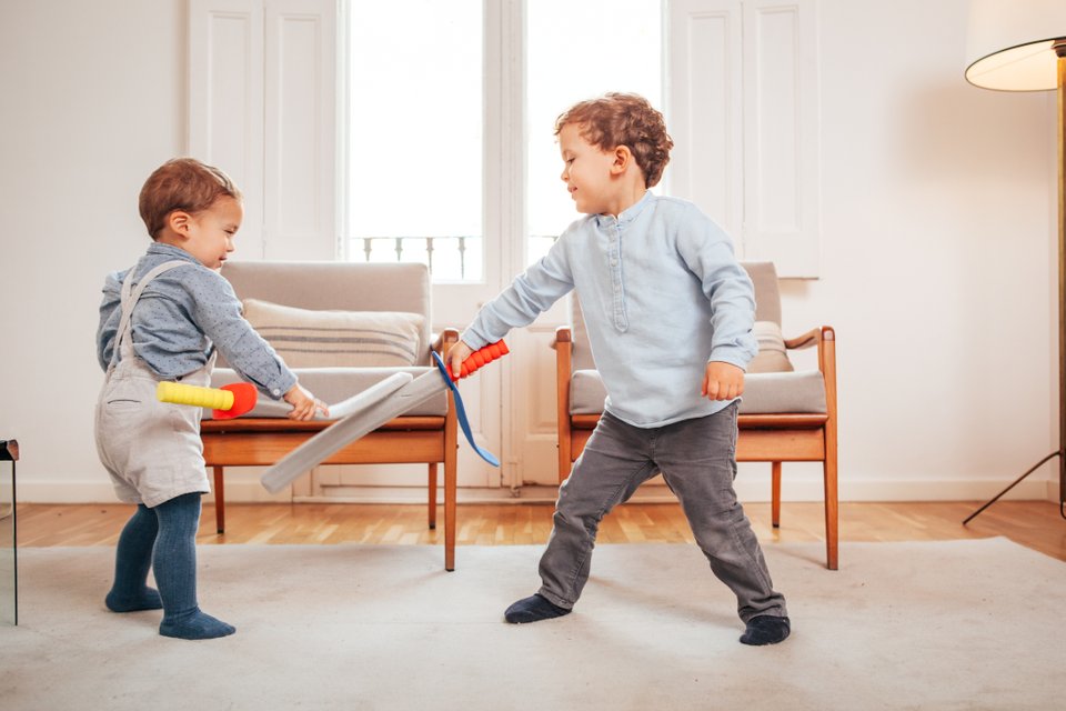duas crianças brincando com espadas de brinquedo