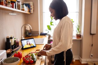 mulher na cozinha cortando legumes usando um smart display