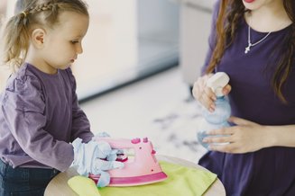 adulto e criança brincando com ferro de passar de brinquedo