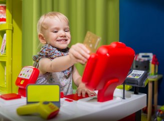 criança com um mercadinho de brinquedo passando um cartão