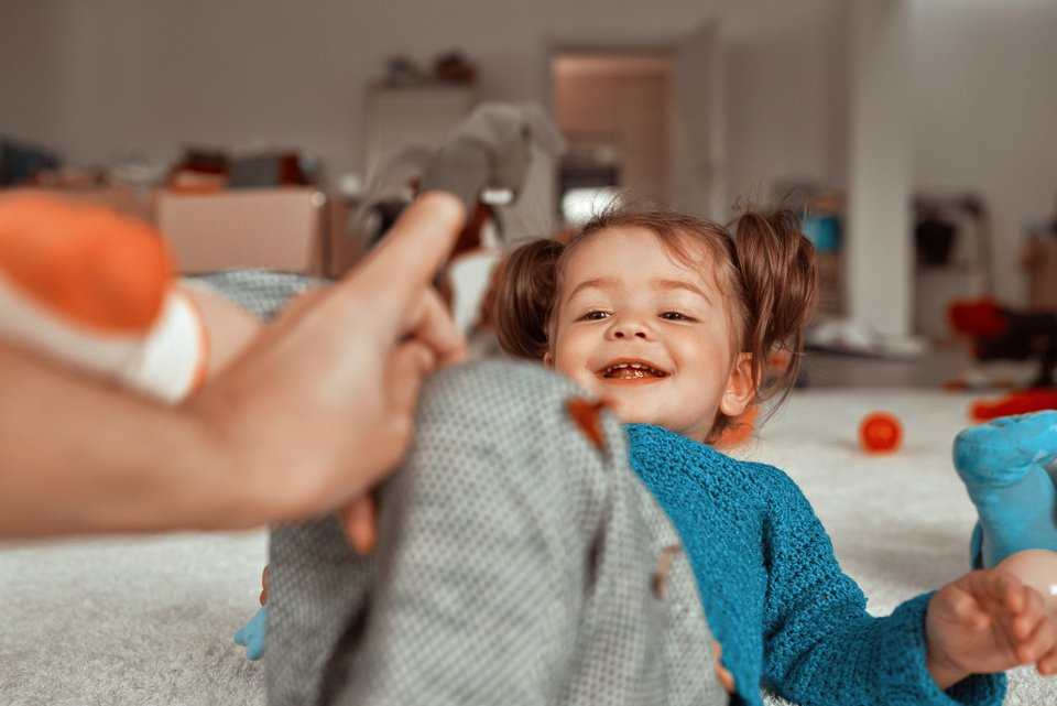 criança deitada e uma mão de um adulto com um fingerling