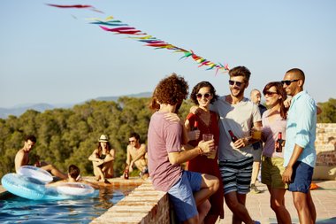 jopvens na beira da piscina com drinks na mão