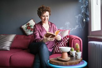 mulher lendo livro sentada em um sofá