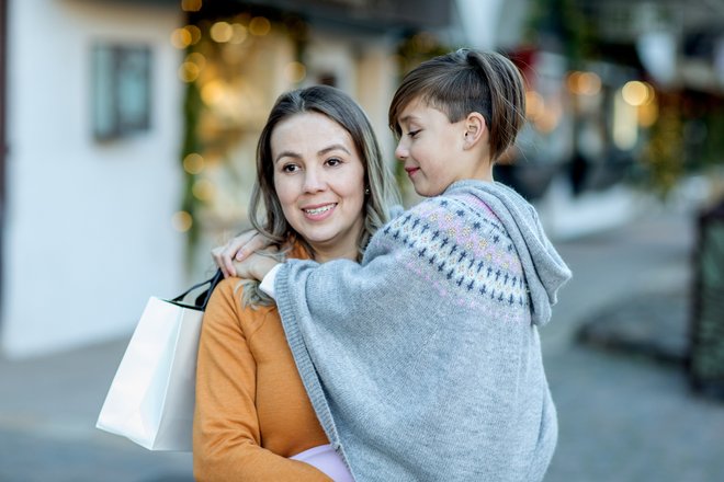 criança com poncho no colo de uma mulher