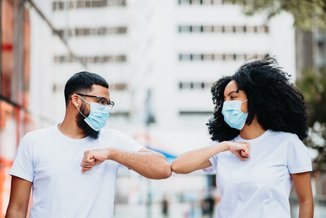 homem e mulher se cumprimentando com o cotovelo e usando máscaras