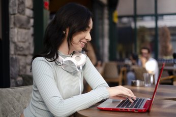 mulher com notebook e fone de ouvido no pescoço