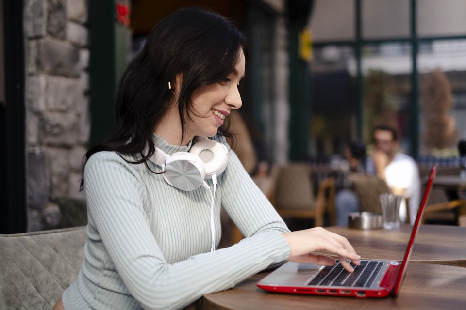 mulher com notebook e fone de ouvido no pescoço