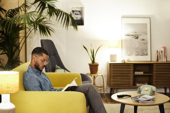 homem sentado em sofá amarelo lendo livro