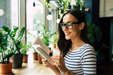 mulher lendo livro com várias plantas ao fundo