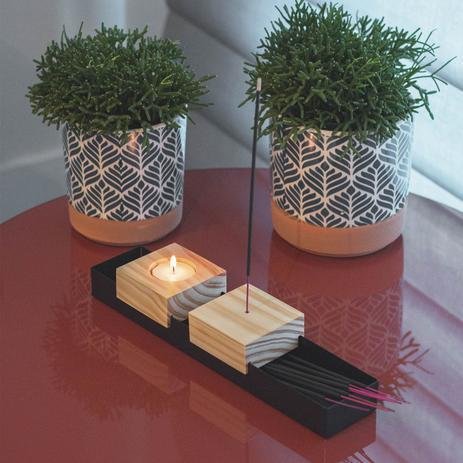 mesa com uma vela ao lado de um incenso e dois vasinhos plantas atrás