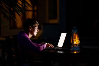 adolescente usando notebook com uma lanterna ao lado