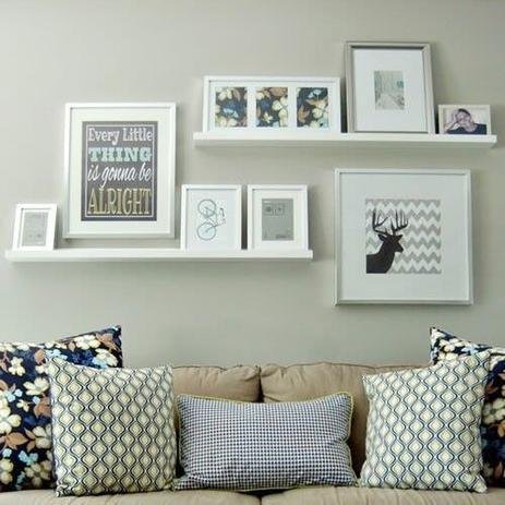 parede com sofá com almofadas e prateleiras com vários quadros