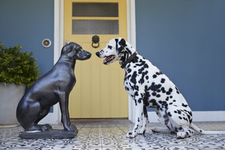 estátua de cachorro na frente de casa e um cachorro de verdade em frente a estátua