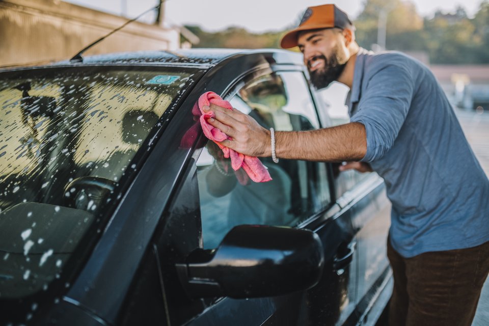 homem usando uma flanela no vidro do carro