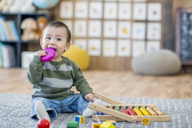 bebê sentado no chão brincando com brinquedos