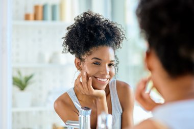 mulher negra com cabelo cacheado se olhando no espelho