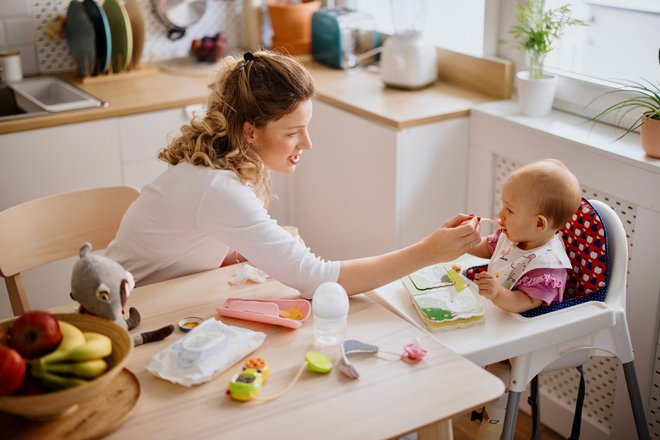 criança em cadeira de alimentação sendo alimentada por mulher