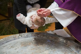 criança sendo batizada com água na cabeça
