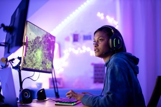 jovem usando fone gamer em frente a tela de computador