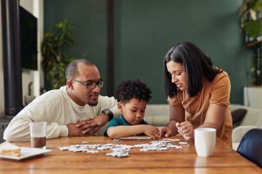 homem mulher e criança montando quebra-cabeça