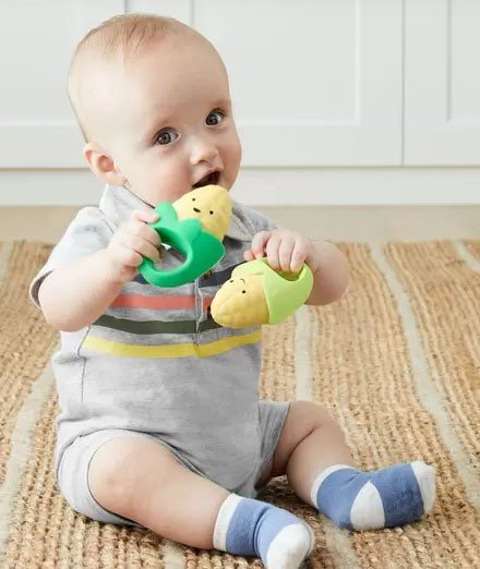 bebê com duas maracás nas mãoes em formato de espiga de milho