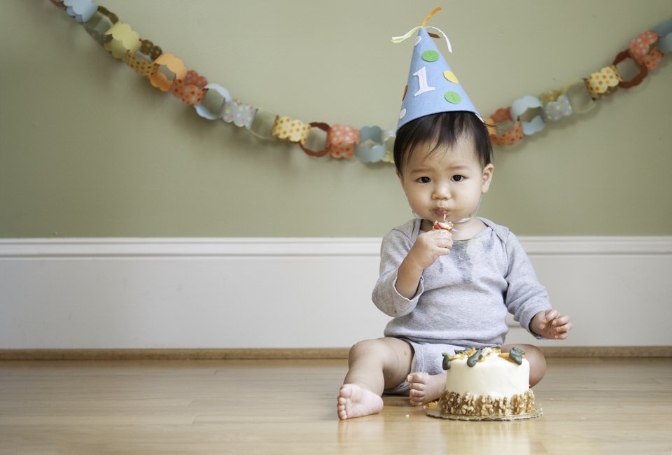 criança sentada no chão ao lado de um bolo decorado