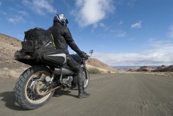 motociclista em cima da moto com mochila na estrada