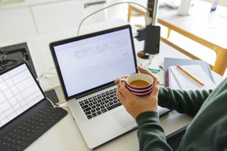 notebook com uma pessoa segurando uma xícara de café