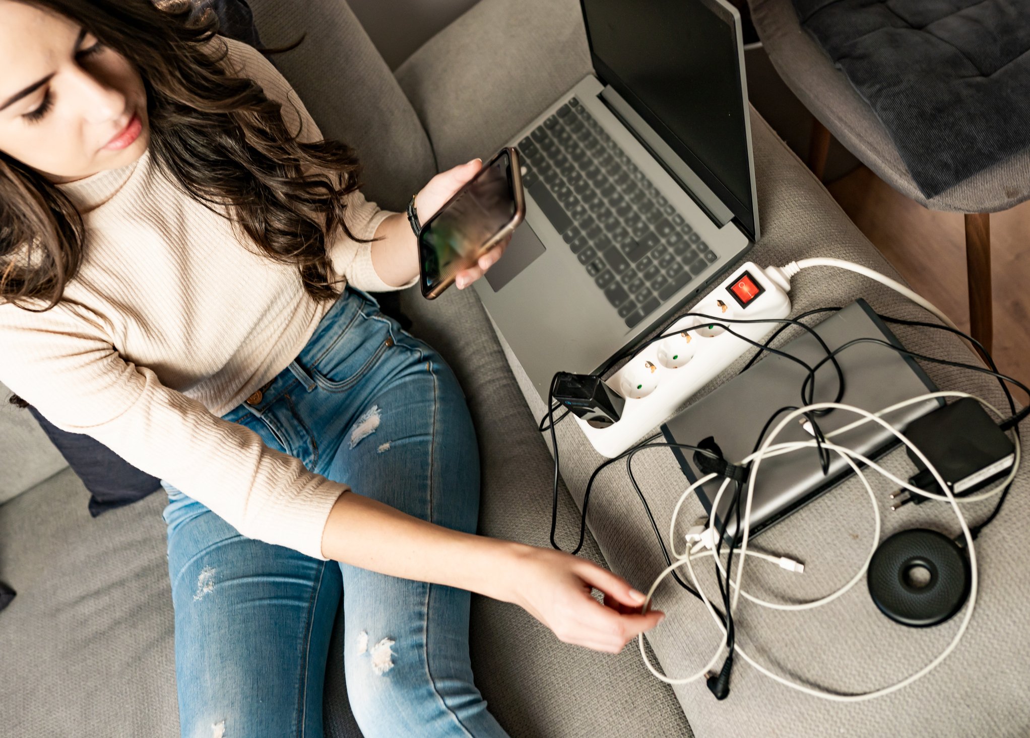 mulher com notebook, smartphone e vários fios