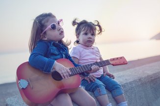 duas crianças e uma delas está tocando violão