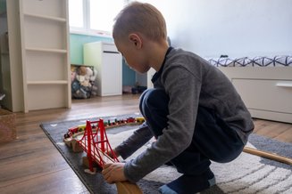 criança brincando nochão com pista de trem