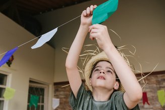 menino arrumando vandeirinhas de festa junina