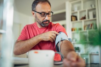 homem com medidor de pressão no braço