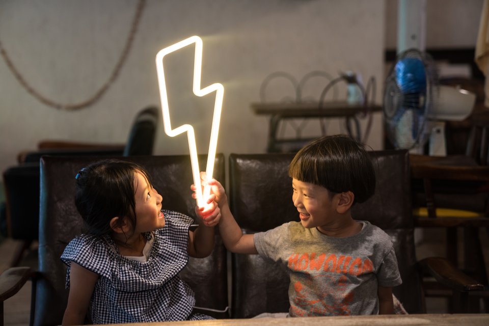 duas crianças segurando um raio de eletricidade