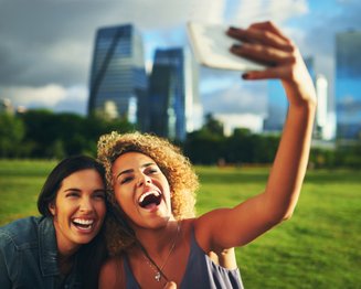 duas mulheres tirando selfie ao ar livre