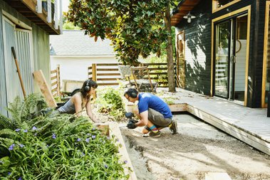 homem e mulher em um jardim manuseando cimento