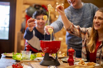 dois homens e uma mulher comendo fondue