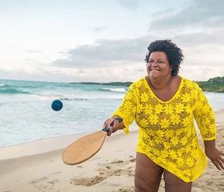 mulher na praia com raquete na mão e saída de praia amarela