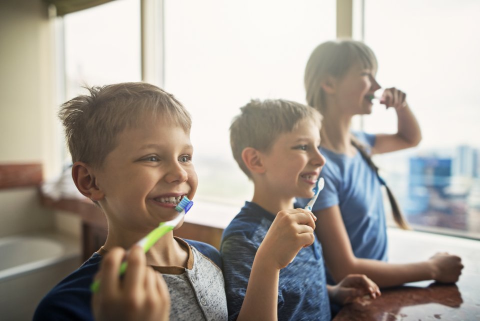 trÊs crianças escovando os dentes