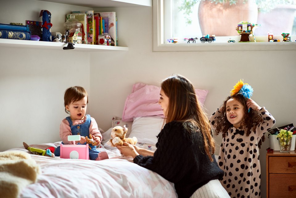 um bebê, uma criança e uma mulher brincando na cama