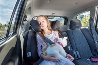 criança dormindo no carro usando apoio para cabeça