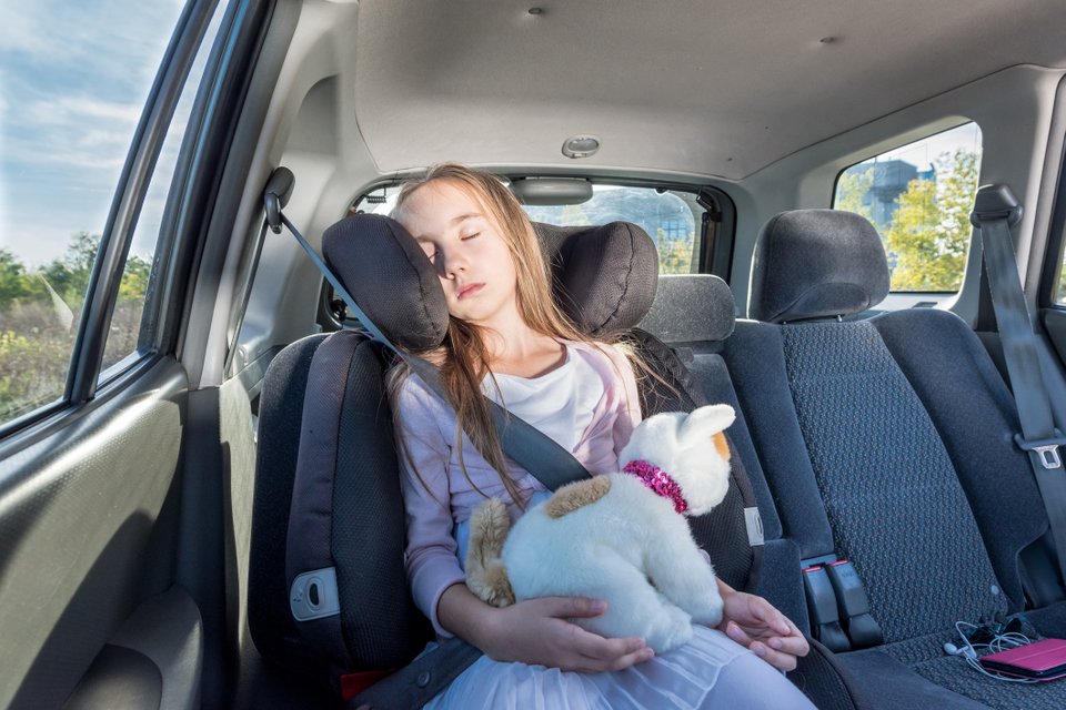 criança dormindo no carro usando apoio para cabeça