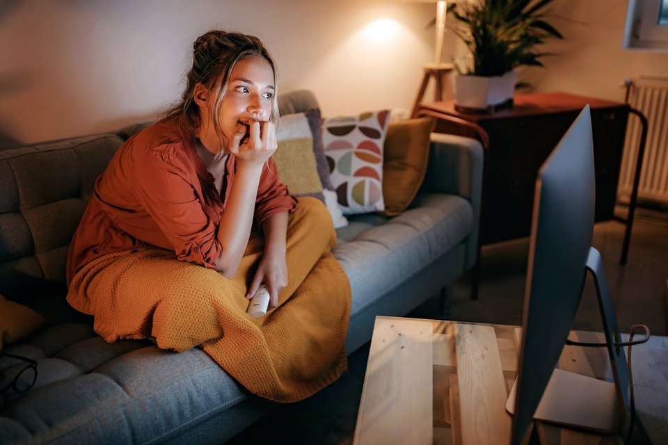 mulher sentada no sofá olhando pra um monitor