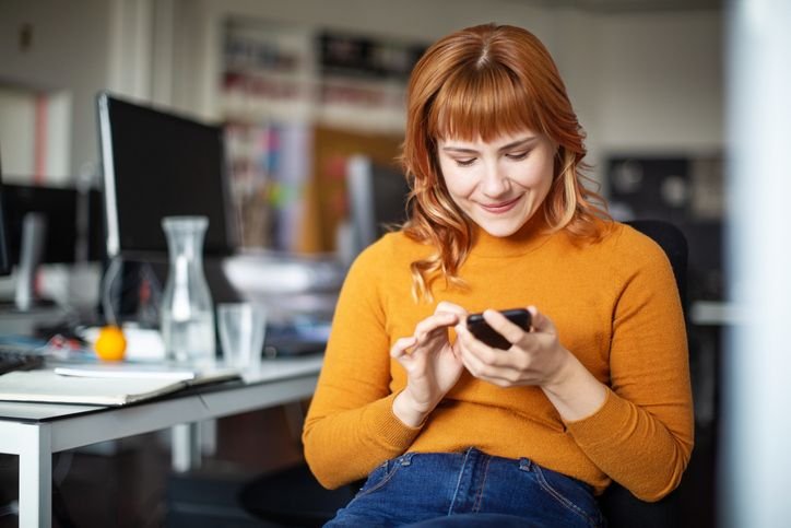 Mulher usando smartphone Redmi 14C no escritório com expressão concentrada.