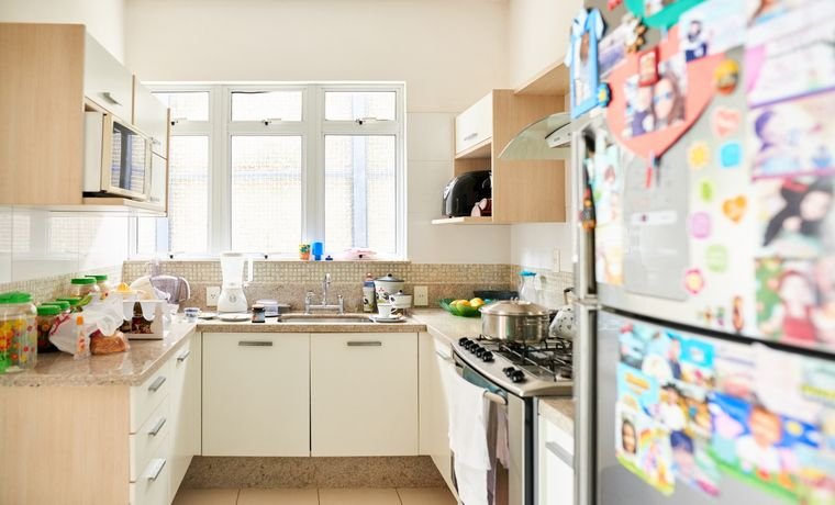 Arm&aacute;rios de cozinha que ajudam a organizar o ambiente. Na imagem tamb&eacute;m aparecem eletrodom&eacute;sticos.
