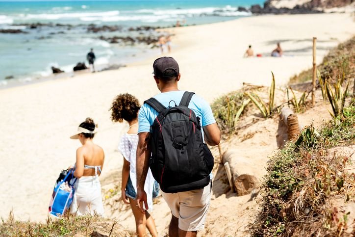 Homem com mochila mormaii descendo pra praia.